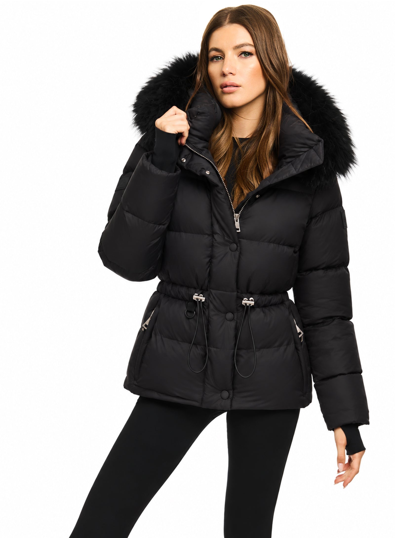 DELANEY A woman modeling a black puffer jacket with a large black fur-trimmed hood, belted waist, and silver zipper details, set against a plain white background.