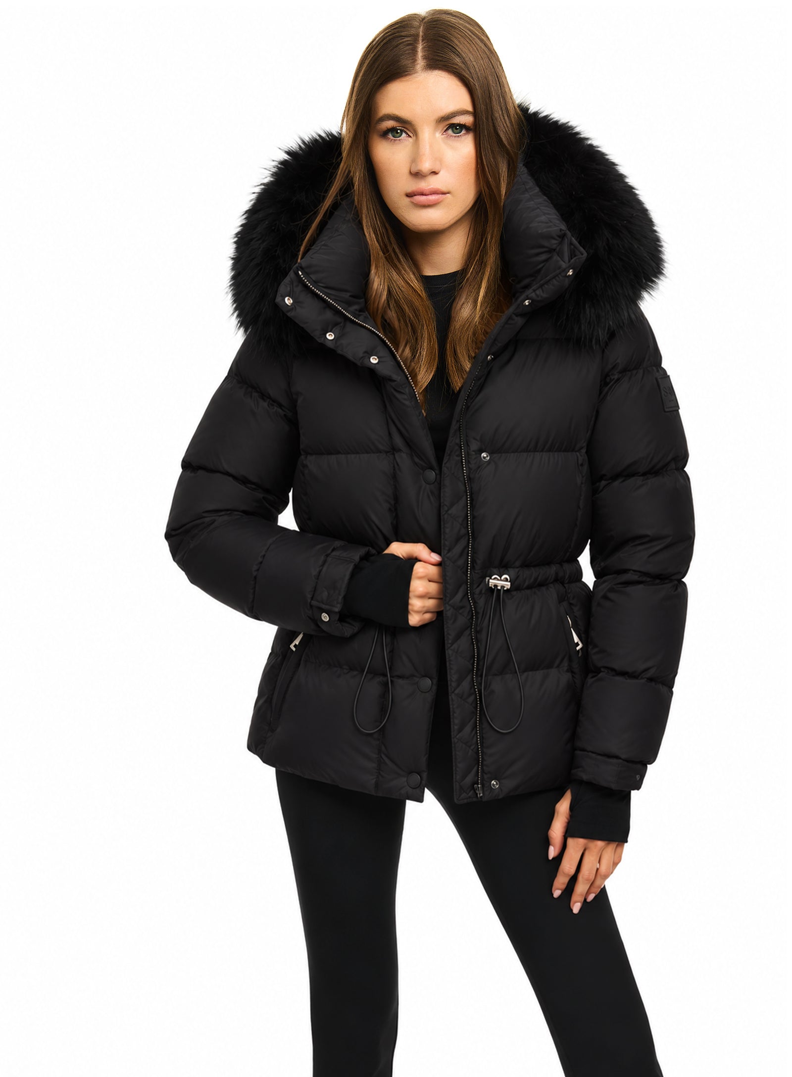 DELANEY A woman modeling a black puffer jacket with a large black fur-trimmed hood, shown against a plain white studio background.