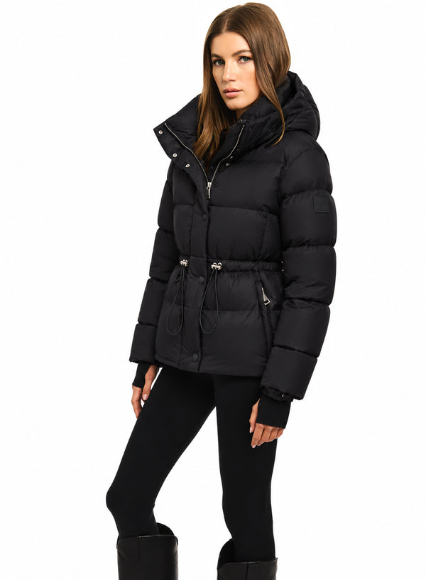 DELANEY A woman modeling a black puffer jacket with a hood, belted waist, and silver zipper details, set against a plain white background.